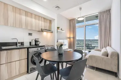 a kitchen and living room with a table and chairs at Contemporary 1BR Home in Damac Hills in Dubai