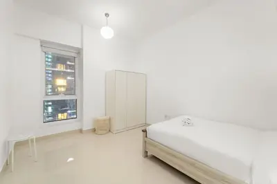 a white bedroom with a bed and a window at FIRST CLASS 2BR Cozy City Retreat in Dubai