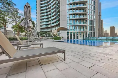 a patio with chairs and an umbrella and a pool at Stylish 2BR Downtown Dubai with Skyline & Burj Khalifa Views in Dubai