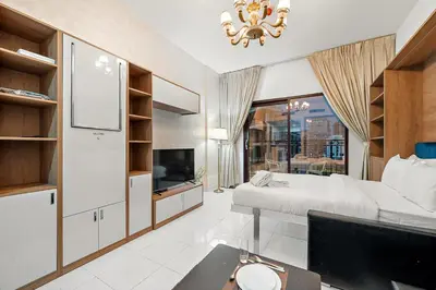 a bedroom with a bed and a tv and a desk at FIRST CLASS Studio Elegant Escape, Cozy Luxe in Dubai