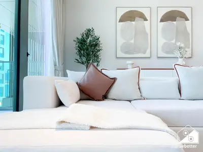 a living room with a white couch with pillows at Luxury Beachfront 1BR on Palm Jumeirah & Balcony in Dubai