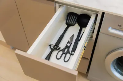 a drawer with utensils in a cabinet next to a washing machine at Elite Escapes - Boy Girl Apartment Edition in Dubai
