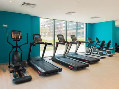 a row of treadmills in a gym with blue walls at Elite Escapes - Boy Girl Apartment Edition in Dubai