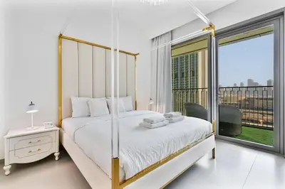 a white bedroom with a bed and a large window at 3BR APT with Burj View from Balcony - Pool and Gym in Dubai