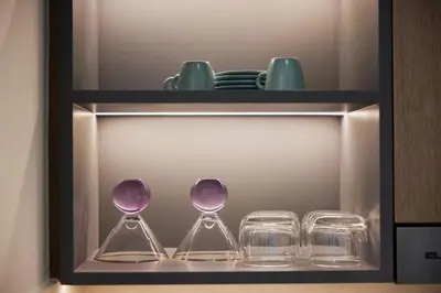 three wine glasses and plates on a shelf at Cozy 1BR Burj Crown Downtown in Dubai