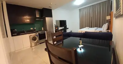 a living room with a dining room table and a kitchen at Capital Bay city view Studio in Dubai