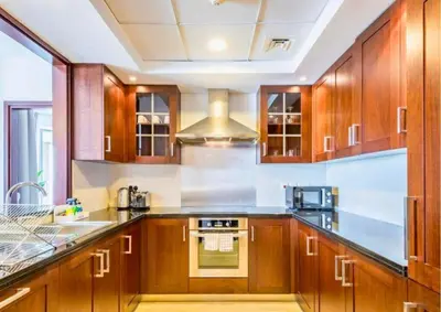 a kitchen with wooden cabinets and a stove top oven at Exceptional 1BR I Burj Khalifa I Fountain View in Dubai