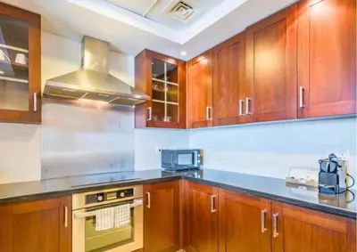 a kitchen with wooden cabinets and a stove top oven at Exceptional 1BR I Burj Khalifa I Fountain View in Dubai