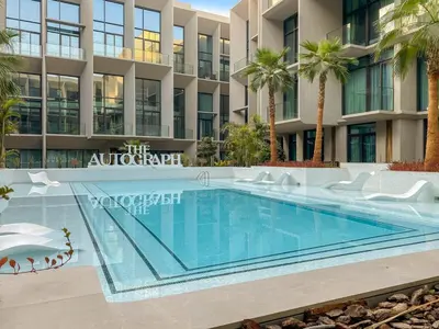 a swimming pool in front of a building with palm trees at Modern Studio Near Burj Khalifa & Dubai Mall with Pool, Gym, Concierge & Parking in Dubai