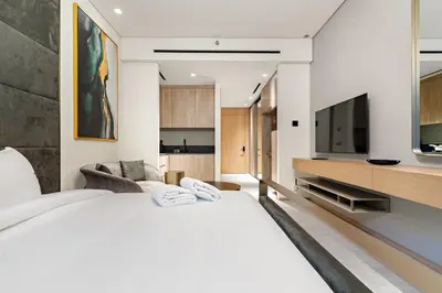a bedroom with a large white bed and a flat screen tv at Modern Studio Near Burj Khalifa & Dubai Mall with Pool, Gym, Concierge & Parking in Dubai