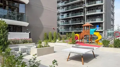 a playground with a slide and a table in front of a building at Modern Studio in JVC, Rooftop Pool & Gym Access - 10AB08 in Dubai