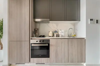 a kitchen with a stove and a sink and cabinets at FIRST CLASS Studio Luxe & Cozy Vibes in Dubai