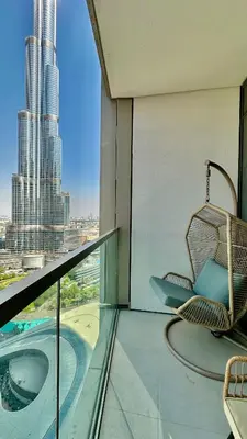 a chair on a balcony with a view of a city at Grande Signature Burj Khalifa view 4 Min walk Dubai Mall Infinity Pool with Fountain View Free parking By The Meridian in Dubai