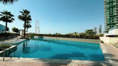 a swimming pool with a ferris wheel in the background at SkyHigh Stay, Panoramic Sea Views & Beach Access in Dubai