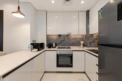 a kitchen with white cabinets and a stove top oven at Nobles Tower tiger one skyline view in Dubai