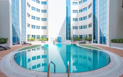a swimming pool in the middle of a building at Studio with Balcony Overlooking the Community, Walking Distance from the Park, Hanover Square HSS, Jumeirah Village Circle by Deluxe Holiday Homes in Dubai