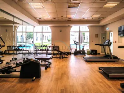a gym with several treadmills and exercise machines at Studio with Balcony Overlooking the Community, Walking Distance from the Park, Hanover Square HSS, Jumeirah Village Circle by Deluxe Holiday Homes in Dubai