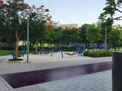 an empty park with blue swings and trees at Air Homes - Stylish 2BR Near Dubai Hills Mall & Park in Dubai