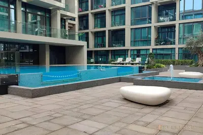 a large building with a swimming pool in front of it at Contemporary Studio Terrace Luxe & Secure Stay in Dubai