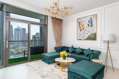 a living room with a green couch and a large window at Stylish 2BR with Boulevard View & 5 min from Dubai Mall in Dubai
