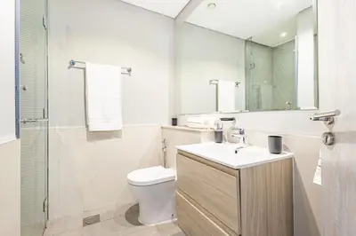 a bathroom with a toilet and a sink and a mirror at Modern 1BR in Business Bay - Balcony with Skyline Views in Dubai