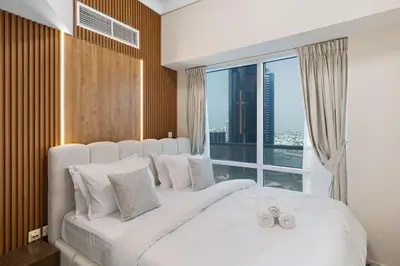 a bedroom with a white bed with a large window at Elegant Haven and Spacious 2BR in Lake Terrace in Dubai