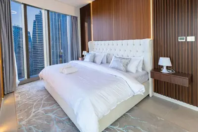 a bedroom with a large white bed with a large window at Luxury Grande 2BR Near DubaiMall in Dubai