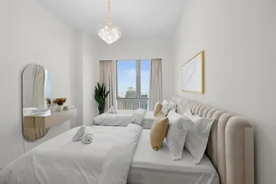 a white bedroom with two beds and a large window at Luxury 2BR Apartment in Downtown Dubai in Dubai