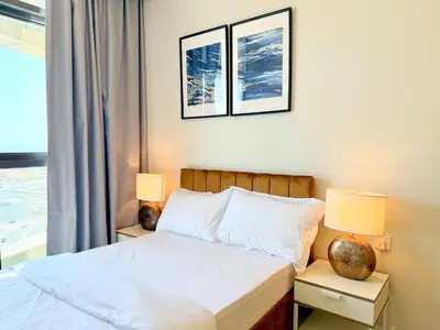 a bedroom with a bed with two lamps and a window at Cozy Two Bedroom Apartment in Dubai