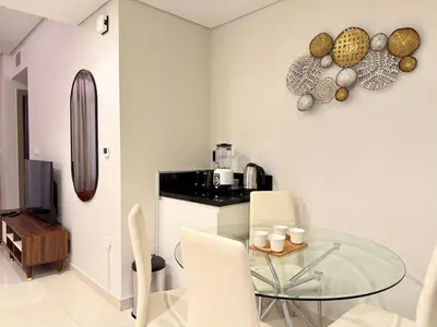 a dining room with a glass table and white chairs at Cozy Two Bedroom Apartment in Dubai