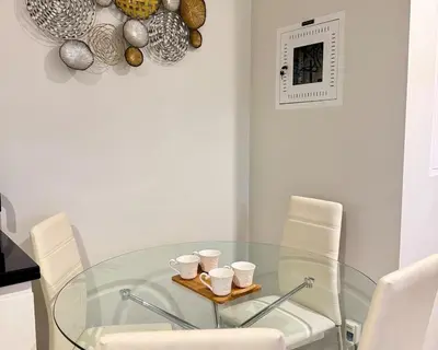 a glass dining room table with white chairs and cups at Cozy Two Bedroom Apartment in Dubai