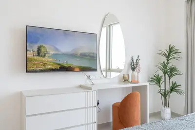 a white bedroom with a painting on the wall at Lux 3 BR & Maidroom Burj & Fountain View 1Gbps WIFI in Dubai