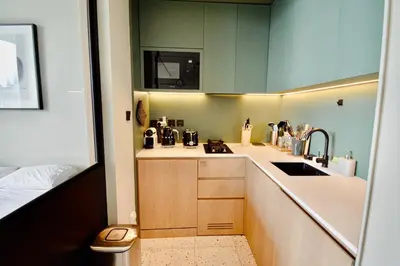 a small kitchen with green cabinets and a sink at Modern Studio at Upside Living, Business Bay with Burj Khalifa View in Dubai