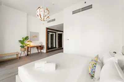a white bedroom with a white bed and a table at Garden Hideaway 2BR Boho Duplex Resort Living in Dubai