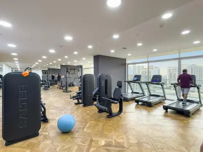 a gym with treadmills and a man walking in it at Garden Hideaway 2BR Boho Duplex Resort Living in Dubai