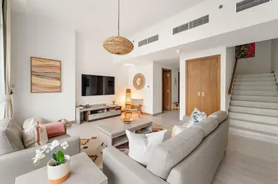 a living room with a couch and a tv at Garden Hideaway 2BR Boho Duplex Resort Living in Dubai