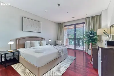 a bedroom with a large bed and a balcony at bnbme - Luxury Anantara Palm Apt Beachfront Lagoon Pools Balcony & Spa Access in Dubai