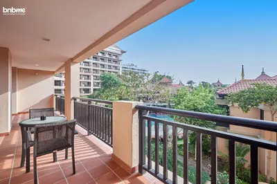 a balcony with a table and chairs on a balcony at bnbme - Luxury Anantara Palm Apt Beachfront Lagoon Pools Balcony & Spa Access in Dubai