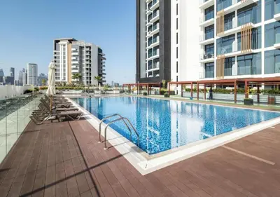 a large swimming pool in a city with buildings at Bespoke Holiday Homes - Studio with Modern Amenities in Azizi Riviera in Dubai
