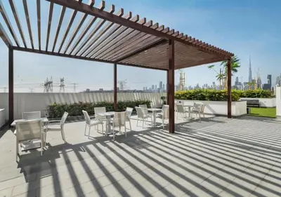 a patio with tables and chairs under a pergola at Bespoke Holiday Homes - Studio with Modern Amenities in Azizi Riviera in Dubai