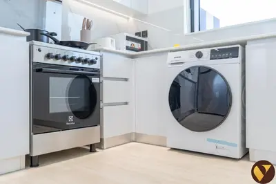 a kitchen with a washing machine and a stove at Vogue JVC Binghatti Corner near Circle Mall, Two Bedroom Apartment with Balcony and City View, Access to all Amenities in Dubai
