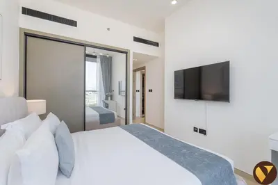 a bedroom with a white bed with a flat screen tv at Vogue JVC Binghatti Corner near Circle Mall, Two Bedroom Apartment with Balcony and City View, Access to all Amenities in Dubai