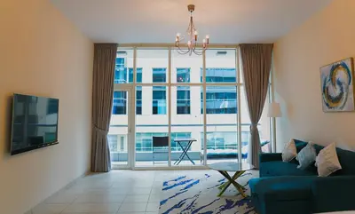 a living room with a blue couch and a large window at Nivis find- Luxury 1 BHK nearby Dubai Mall in Dubai