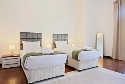 two beds in a room with white walls and wood floors at Luxury 2BR with Contemporary Design & Great Views in Dubai