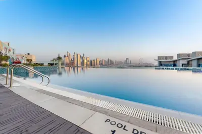a large swimming pool with a city in the background at Stunning Palm Studio - Rooftop Infinity Pool & Private Beach Access - MaxStays in Dubai