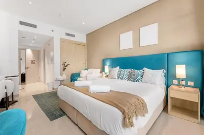 a large bedroom with a large bed with a blue headboard at Stunning Palm Studio - Rooftop Infinity Pool & Private Beach Access - MaxStays in Dubai