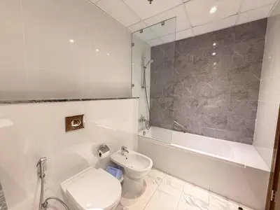 a white bathroom with a toilet and a bath tub at Premium 1BR W Canal & Burj View in Al Habtoor City in Dubai
