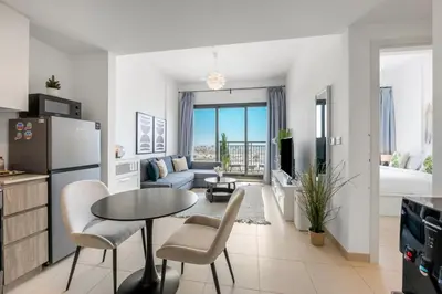 a kitchen and living room with a refrigerator and a table at Waves - Stylish Blue Haven near Town Square Park in Dubai