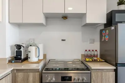 a kitchen with a stove and a refrigerator at Waves - Stylish Blue Haven near Town Square Park in Dubai