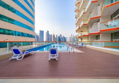a balcony with chairs and a pool in a building at Bespoke Holiday Homes - Upscale 1BR Penthouse in Millenium Binghatti in Dubai